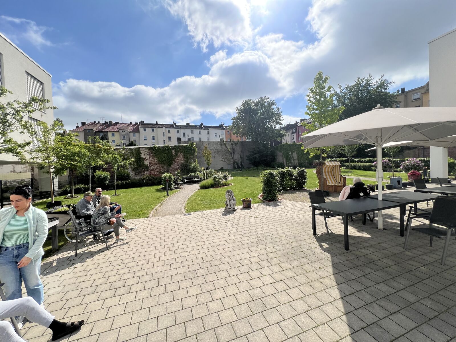 Teilnehmende sitzen in der Sonne im Garten des SHDO Nordstadt
